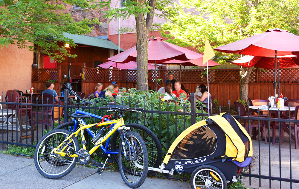 Outdoor dining Patio with bikes and burley leaned up against the fence at Leo's Grill & Malt Shop